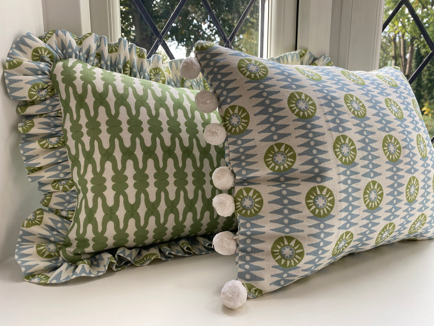 Green cushion with frill plus blue and green cushion with white pompoms. size 45cm by 30cm. feather cushion insert included