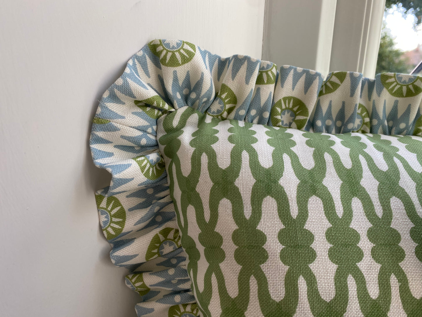 Close up of green cushion with blue and green frill. size 45cm by 30cm. feather cushion pad included