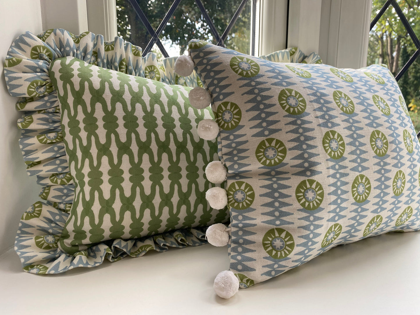 Green cushion with frill plus blue and green cushion with white pompoms. size 45cm by 30cm.  feather cushion insert included