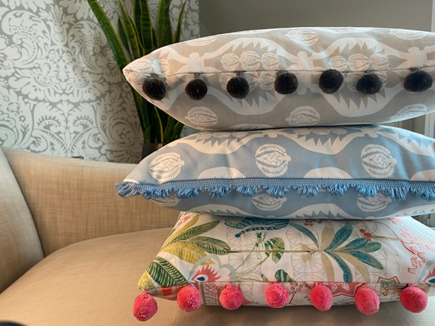 Stack of cushions Georgie fabric grey with pompom trim plus Tiger fabric multi with pompom trim plus Georgie fabric blue and white with fan trim