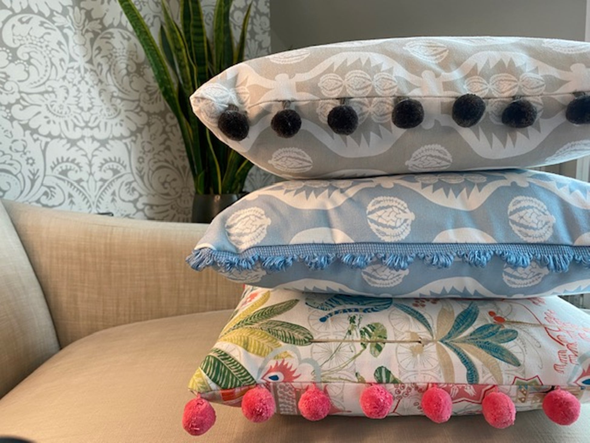 Stack of cushions Tiger fabric multi with pompom trim plus Georgie fabric blue with fan trim plus Georgie fabric grey with pompom trim